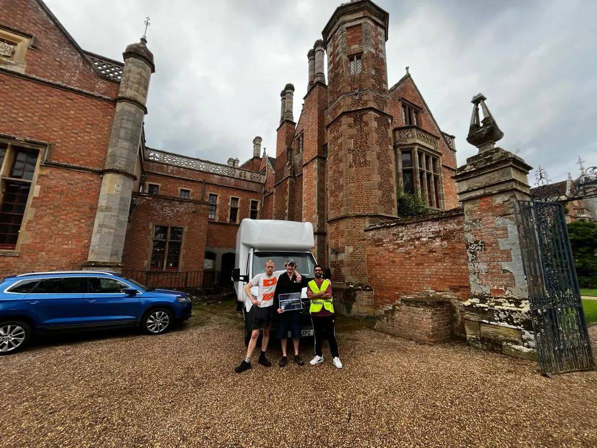Three Fastiya Logistics movers standing in front of their van outside a large house