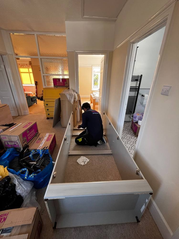 A Fastiya Logistics mover assembling furniture in a hallway