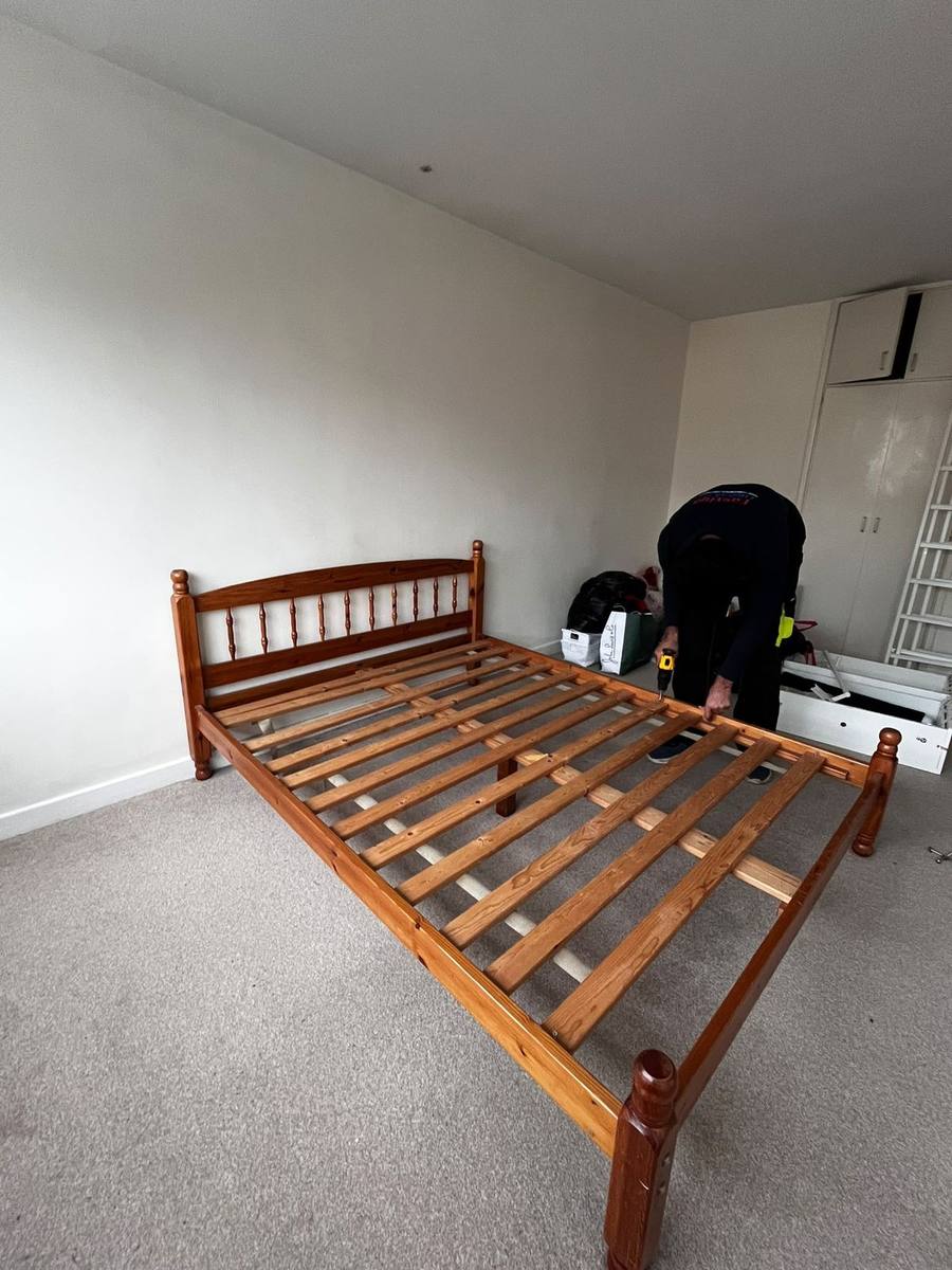A pine bed frame reassembled after a move