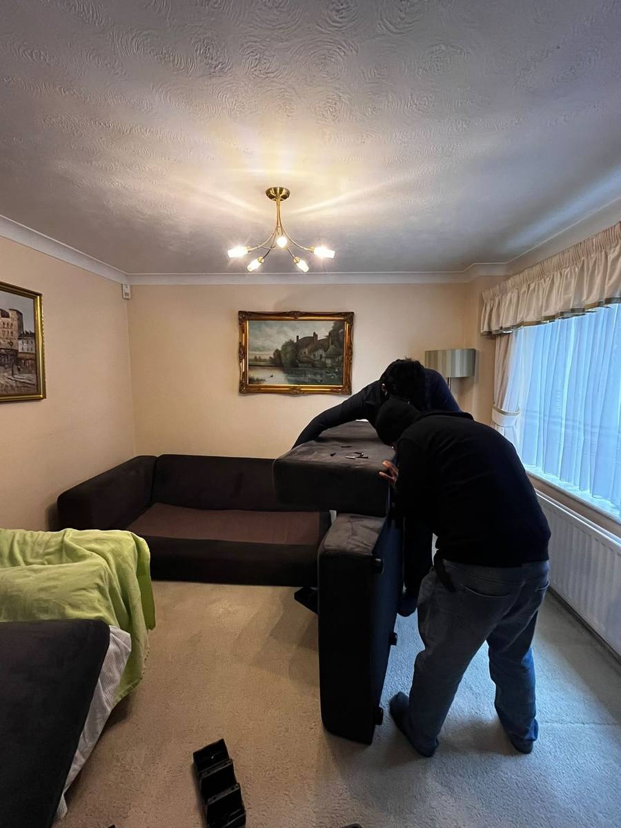 A Fastiya Logistics mover dismantling a sofa in a living room