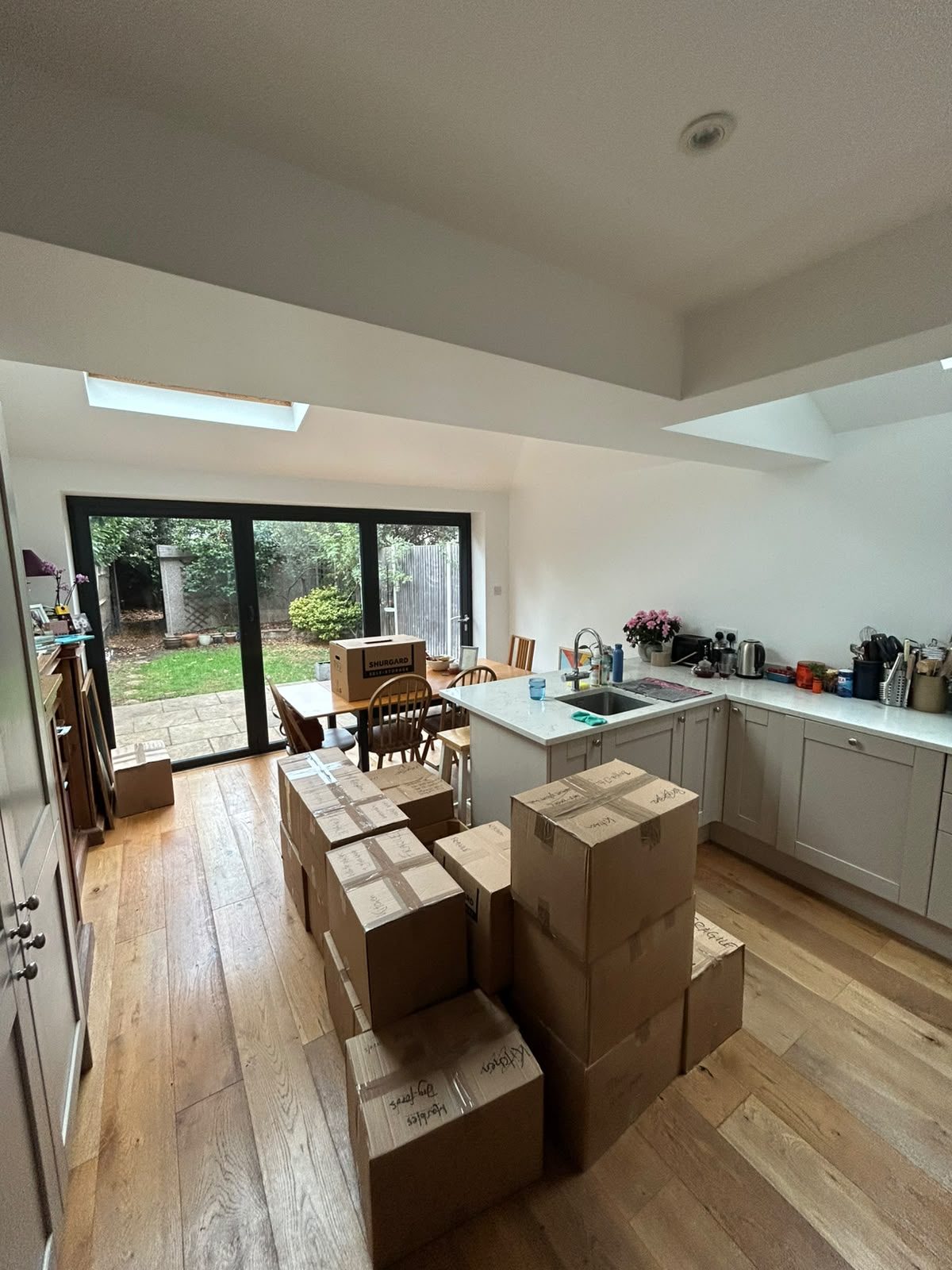 Kitchen packed into boxes, each one taped and labelled with the room and what is inside