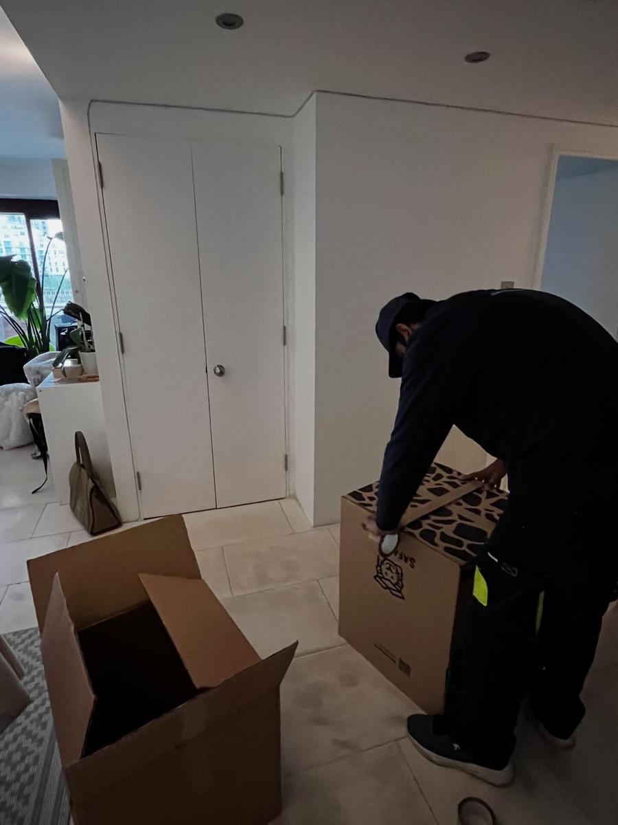 A Fastiya Logistics mover taping a box during a packing job in a London flat