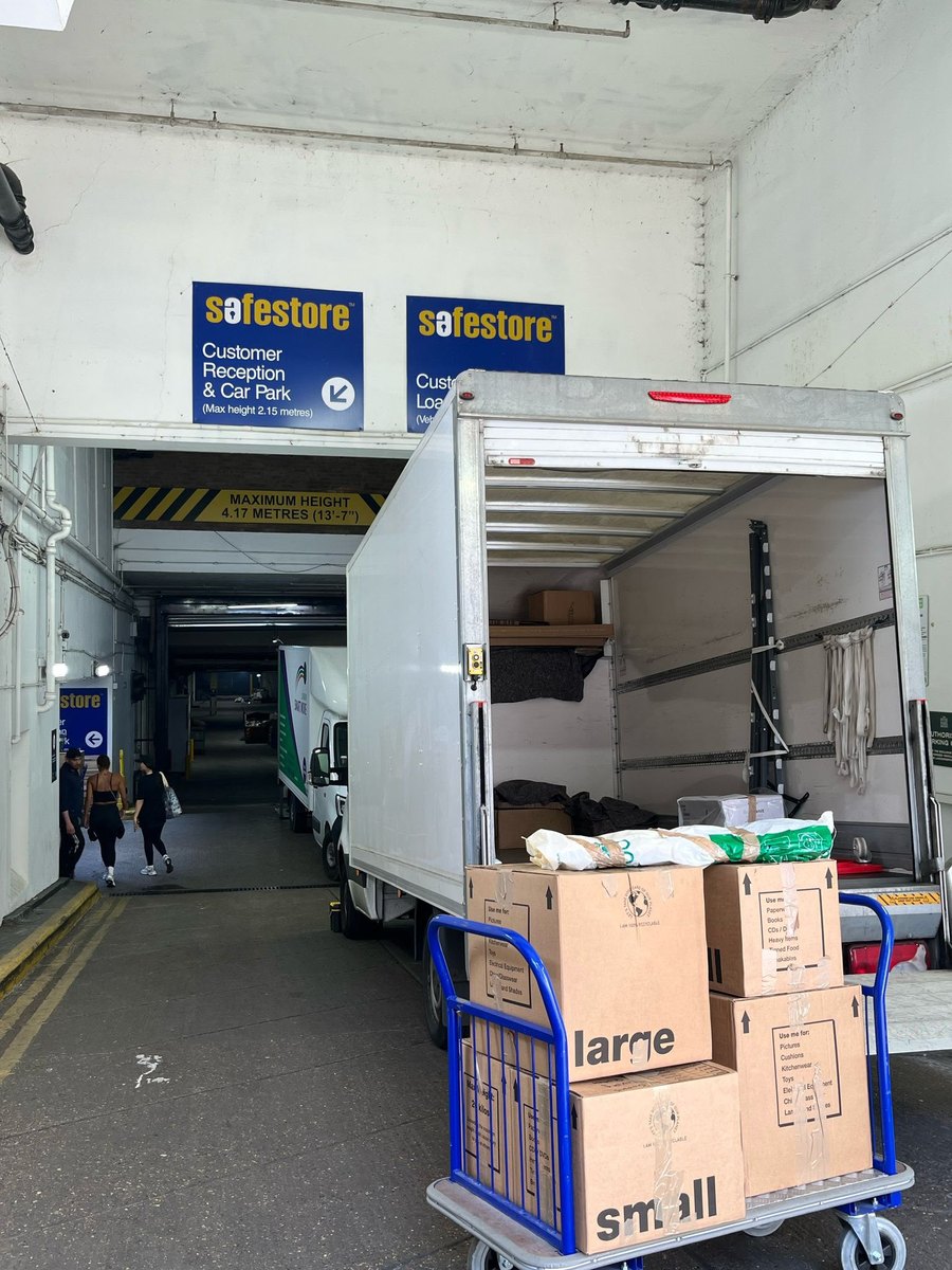 A Fastiya Logistics van at a self-storage loading bay with a trolley of labelled boxes